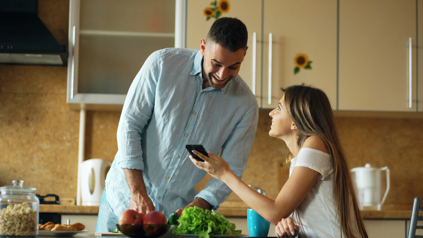 Couple looking at a smartphone together in their kitchen