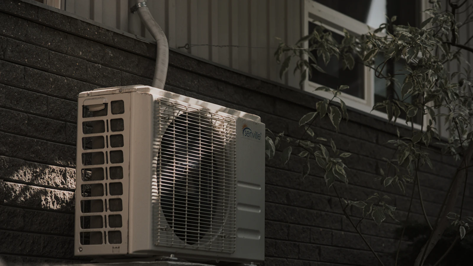 Outdoor air conditioning unit mounted against a dark wall