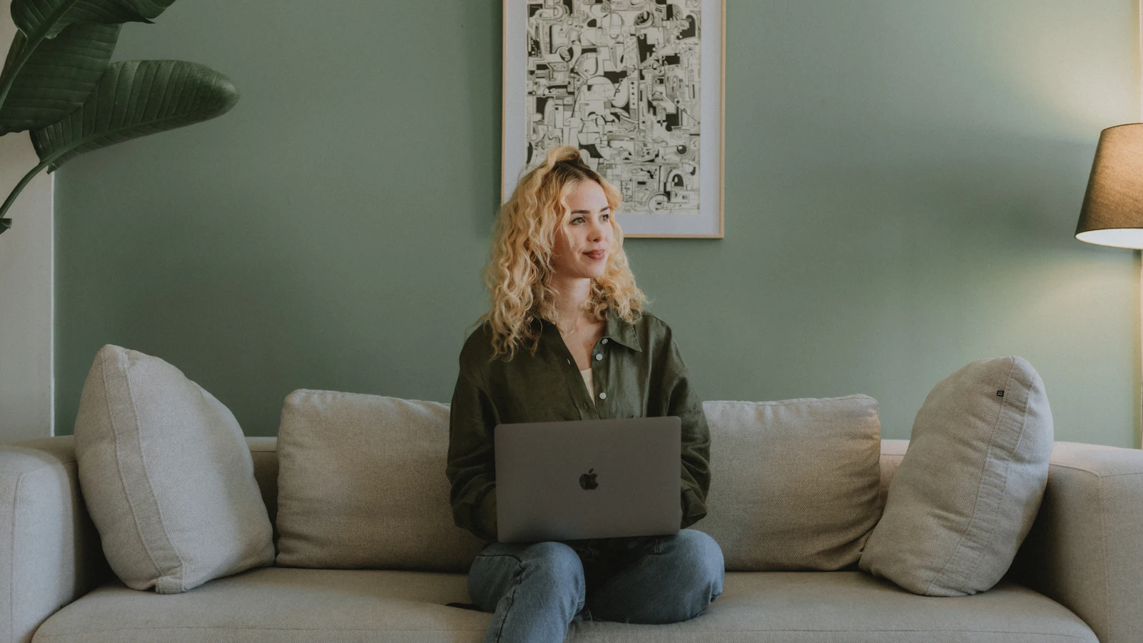 Woman using a laptop on a living room sofa