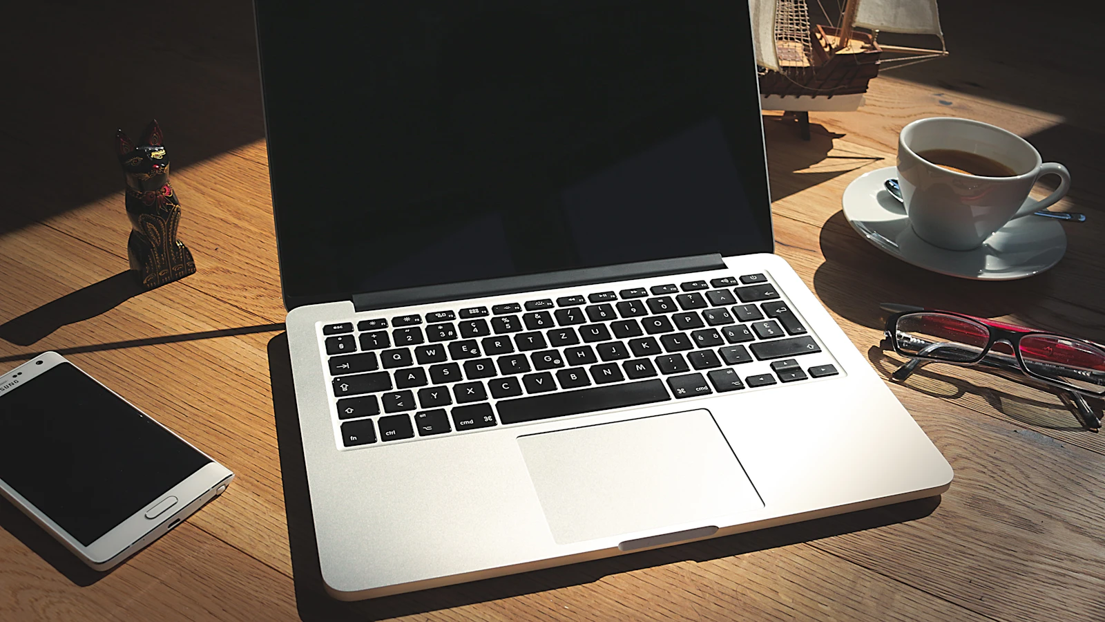 Laptop, phone and coffee on a wooden desk