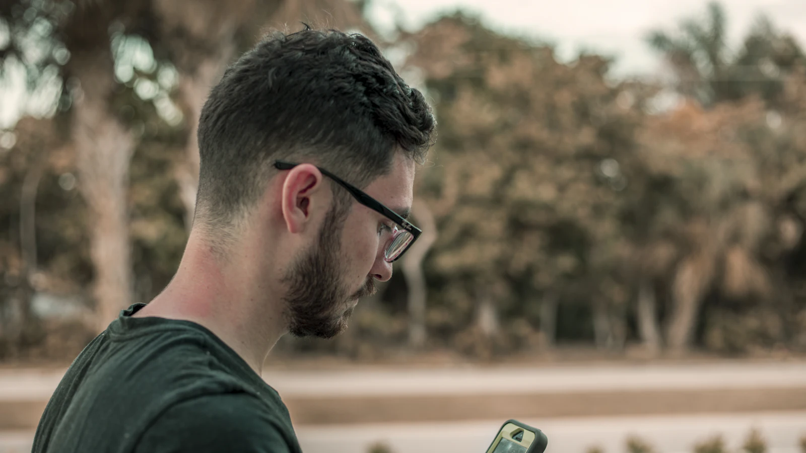 Man reading a text message on his phone outdoors